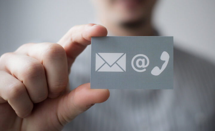 Hand holding a card with email, at sign and phone icons