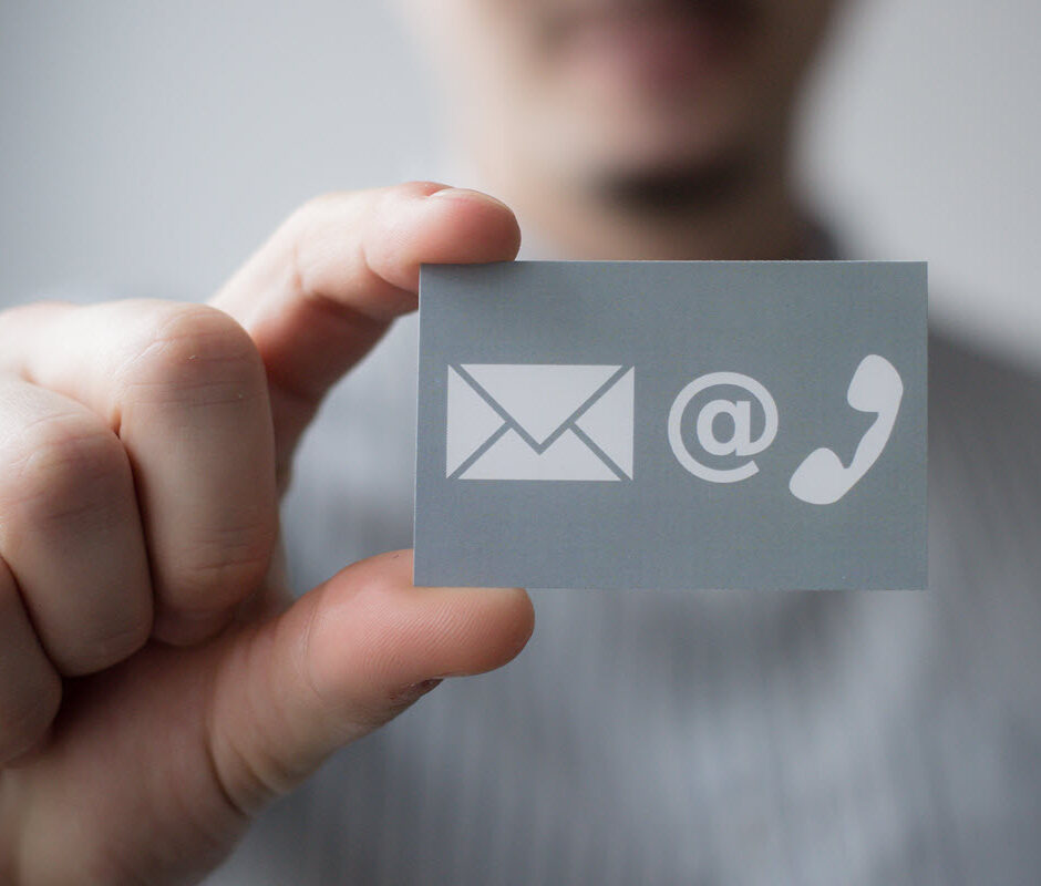 Hand holding a card with email, at sign and phone icons